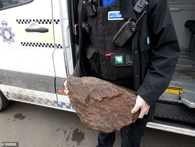 A police officer pictured showing the rock which Bella's cruel former owner had attached to her leash to drown her